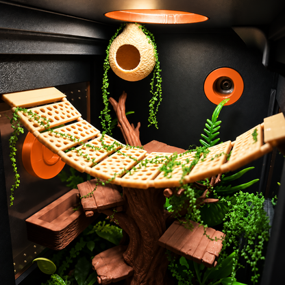 A highly detailed, custom-built treehouse-style habitat or play structure made from natural wood, featuring a curved elevated plank bridge with green trailing vines, multiple wooden platforms, a hanging woven nest, and a faux tree trunk.